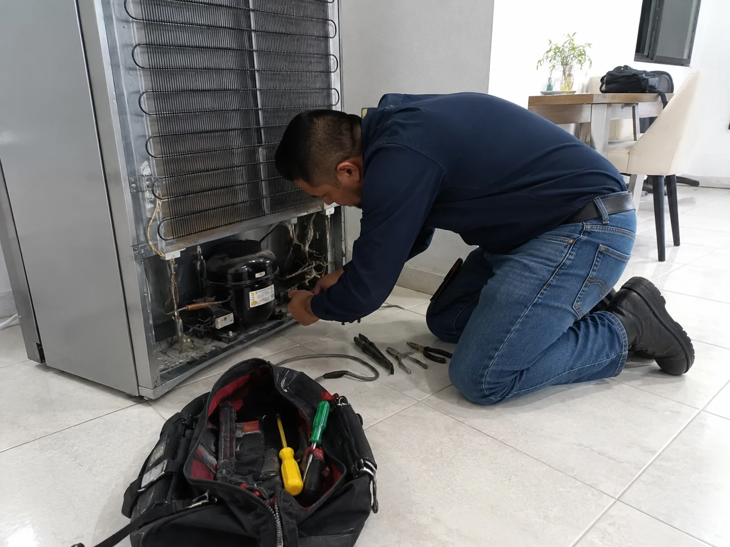 Técnico revisando el compresor de una nevera en Cali